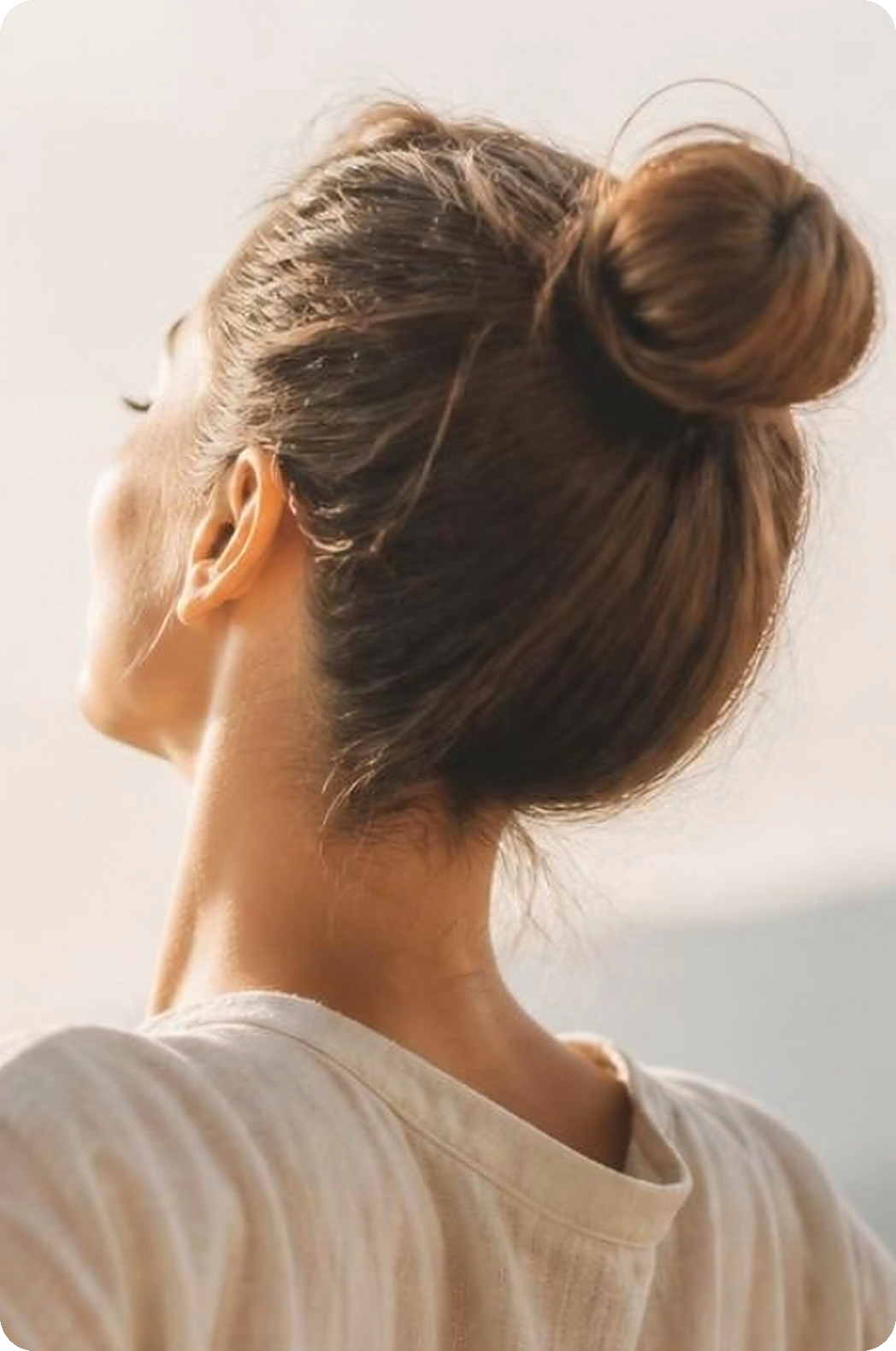Frau mit Haarknoten streckt sich entspannt in der Morgensonne